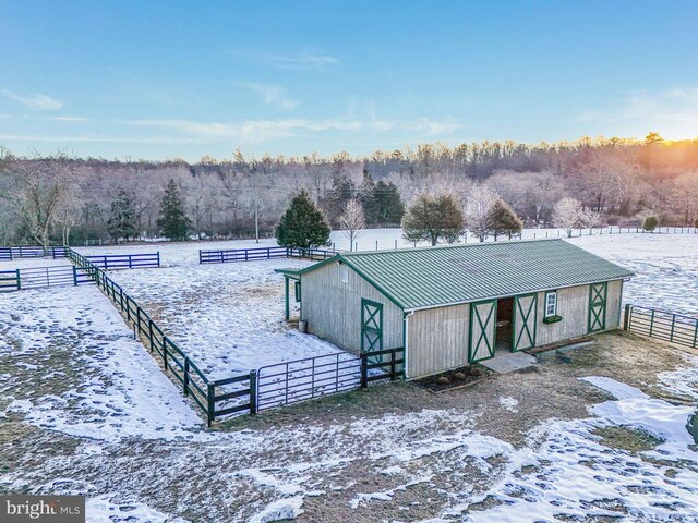 snow covered property with an outbuilding and a rural view