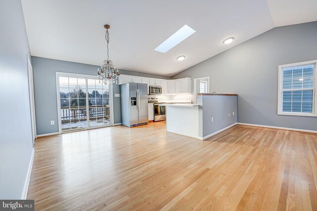 kitchen featuring plenty of natural light, kitchen peninsula, pendant lighting, stainless steel appliances, and white cabinets