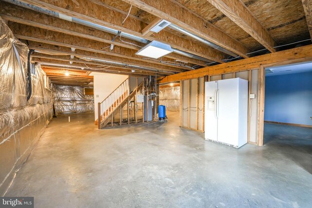 basement featuring white refrigerator with ice dispenser