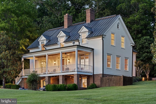 - view of front of property featuring a standing seam roof, a chimney, a front yard, and a ceiling fan