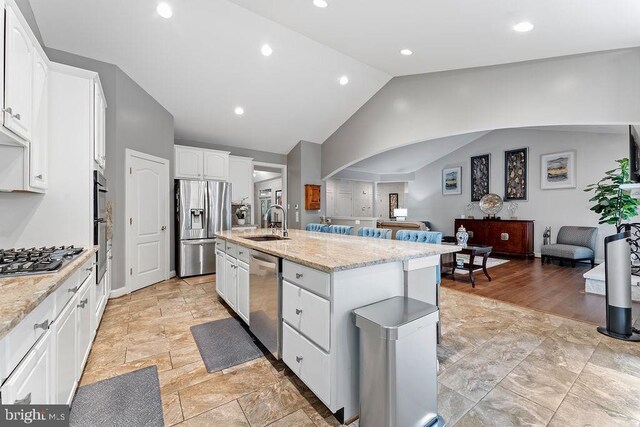 7308 Glenhaven Dr, Fredericksburg, VA 22407 - kitchen with stainless steel appliances, lofted ceiling, white cabinetry, open floor plan, and a center island with sink