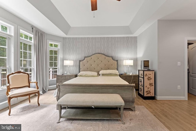7308 Glenhaven Dr, Fredericksburg, VA 22407 - bedroom featuring light wood-type flooring, a raised ceiling, an accent wall, ceiling fan, and wallpapered walls