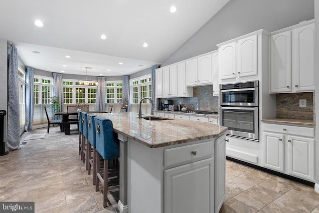 7308 Glenhaven Dr, Fredericksburg, VA 22407 - kitchen featuring appliances with stainless steel finishes, light stone countertops, healthy amount of natural light, tasteful backsplash, and vaulted ceiling