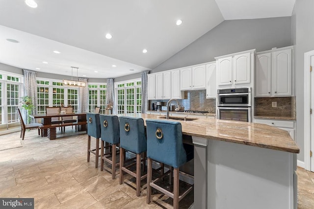 7308 Glenhaven Dr, Fredericksburg, VA 22407 - kitchen with stainless steel double oven, white cabinets, decorative backsplash, a breakfast bar area, and high vaulted ceiling