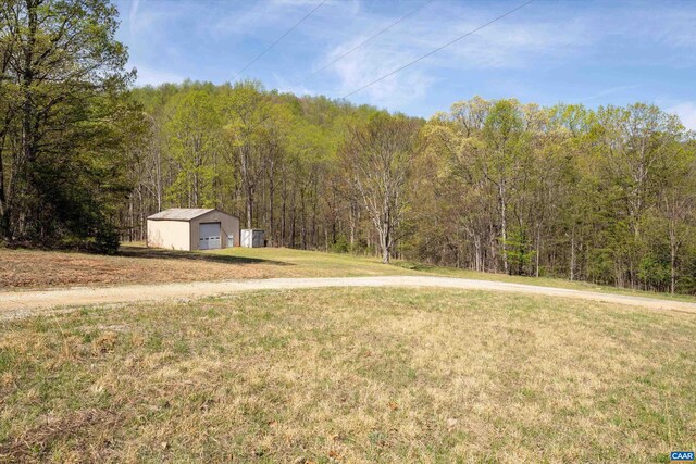 817 Brownings Cv, Shipman, VA 22971 - view of grassy yard with a forest view, an outbuilding, and a garage