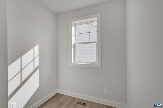 empty room featuring baseboards, light wood-type flooring, and visible vents