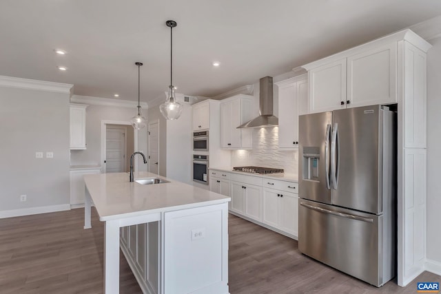 kitchen featuring light countertops, cooktop, stainless steel fridge, a sink, and wall chimney range hood