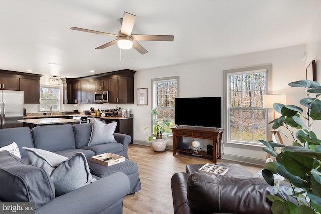 living area with ceiling fan, recessed lighting, baseboards, and light wood-style floors