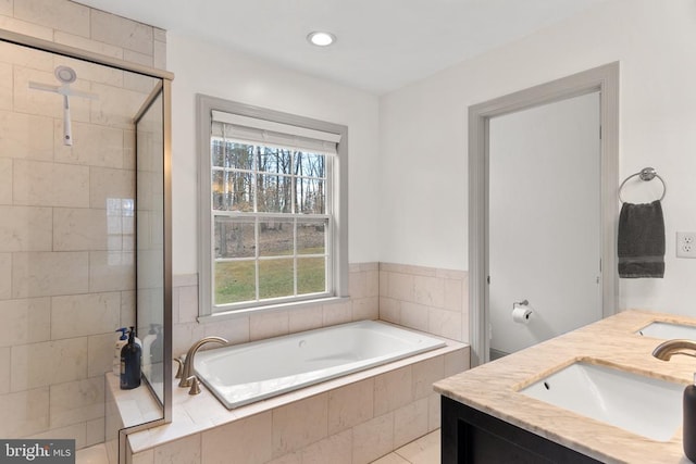 bathroom with double vanity, a stall shower, a sink, a bath, and recessed lighting