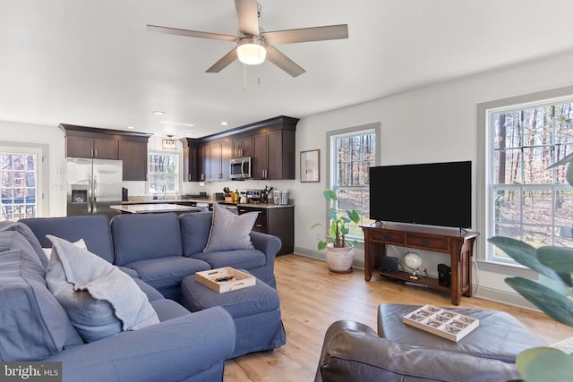 living area with light wood-style flooring, baseboards, ceiling fan, and recessed lighting