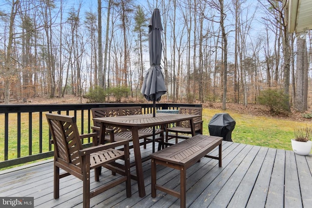 wooden deck featuring outdoor dining space and a lawn