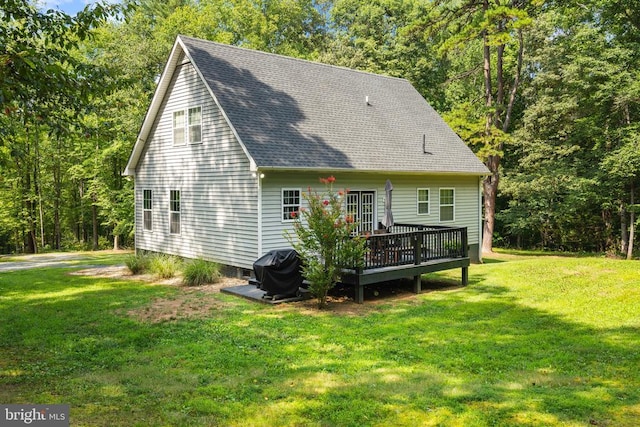 back of house with a deck, a yard, and a shingled roof