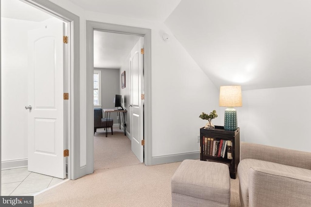 interior space featuring vaulted ceiling, baseboards, and light colored carpet