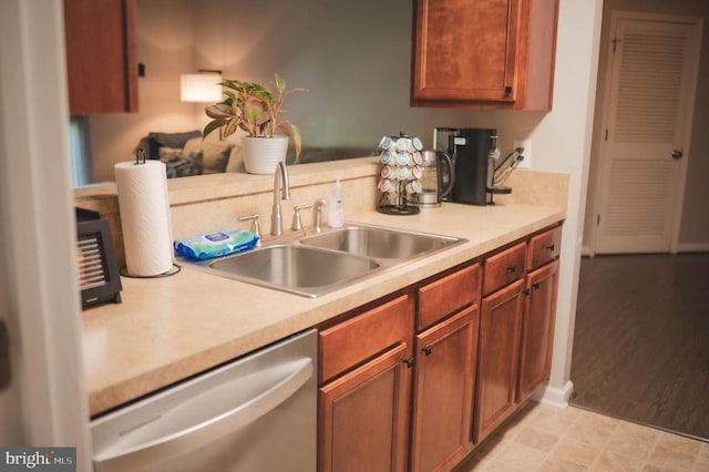 kitchen with dishwasher, a sink, light countertops, and brown cabinets