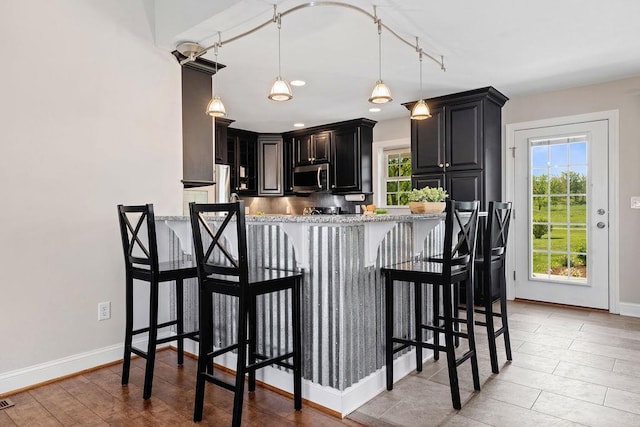 1916 Tinkling Spring Rd, Stuarts Draft, VA 24477 - kitchen featuring stainless steel microwave, dark cabinets, a breakfast bar area, plenty of natural light, and recessed lighting