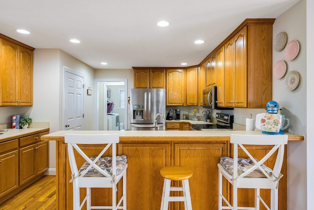 902 Waterton St, Staunton, VA 24401 - kitchen featuring stainless steel appliances, separate washer and dryer, brown cabinets, light wood-type flooring, and a peninsula