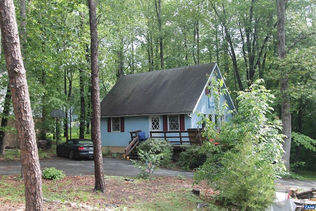 view of front of property featuring roof with shingles, asphalt driveway, and a porch
