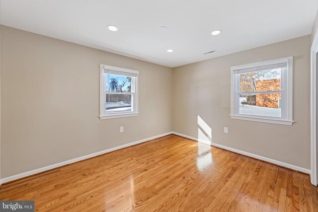 spare room with baseboards, light wood finished floors, and a healthy amount of sunlight