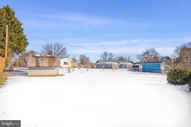 yard covered in snow with an outdoor structure and fence