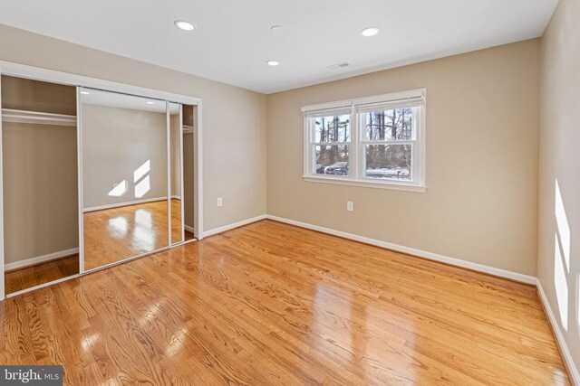 unfurnished bedroom with a closet, baseboards, wood finished floors, and recessed lighting