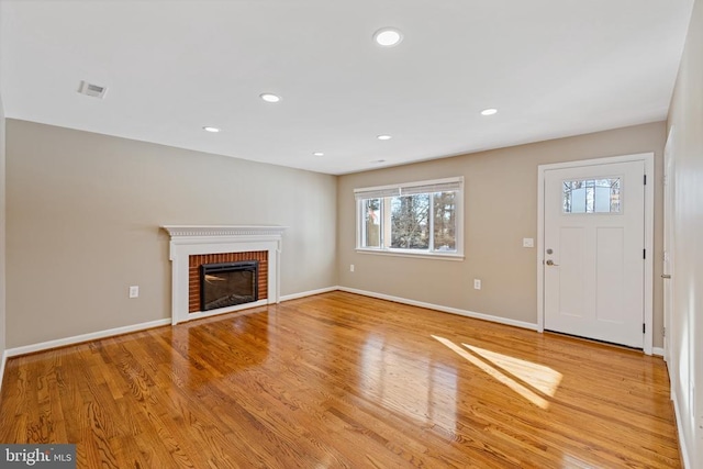 unfurnished living room with a fireplace, light wood-style flooring, and recessed lighting