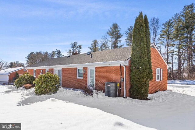 view of front of property with brick siding and central AC