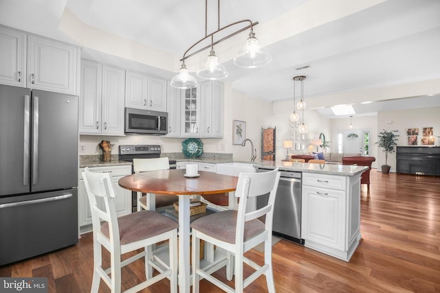 9204 Saint Andrews Ln, Fredericksburg, VA 22408 - kitchen featuring stainless steel appliances, a peninsula, glass insert cabinets, white cabinets, and wood finished floors