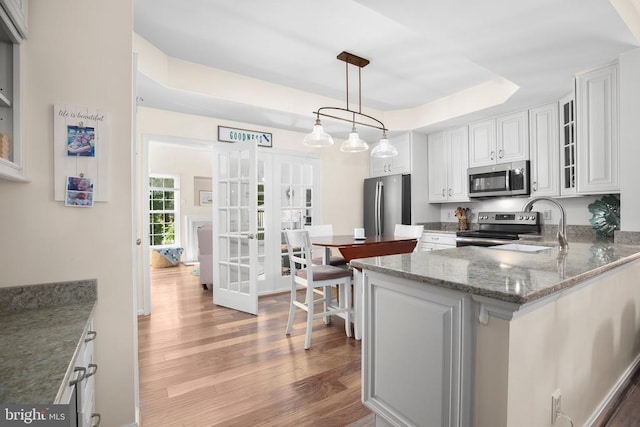 9204 Saint Andrews Ln, Fredericksburg, VA 22408 - kitchen with stainless steel appliances, light wood-style floors, glass insert cabinets, white cabinets, and a raised ceiling
