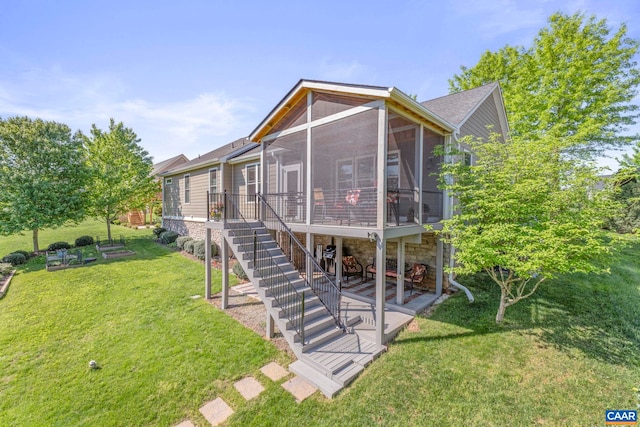 back of house featuring a yard, a sunroom, and stairway