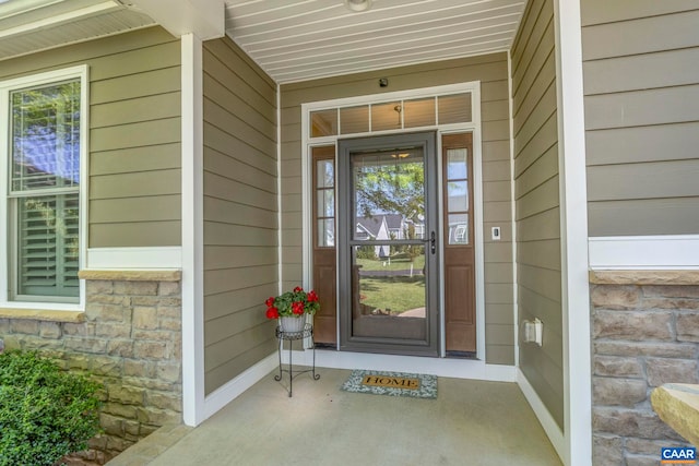 view of exterior entry featuring stone siding and covered porch