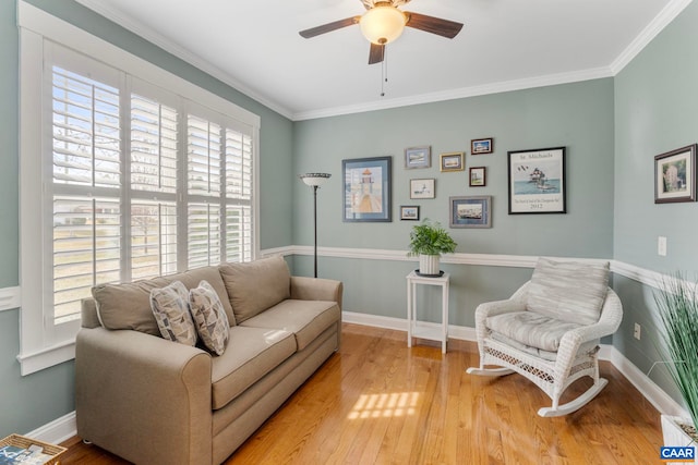 living area with a ceiling fan, wood finished floors, crown molding, and baseboards