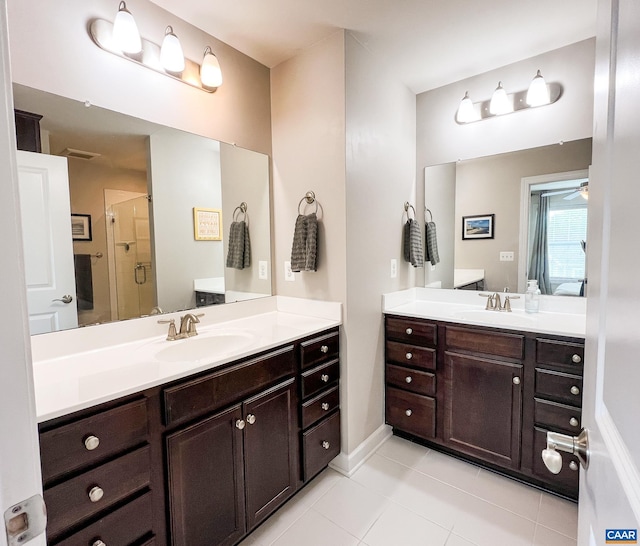 bathroom with tile patterned floors, a shower stall, two vanities, ceiling fan, and baseboards