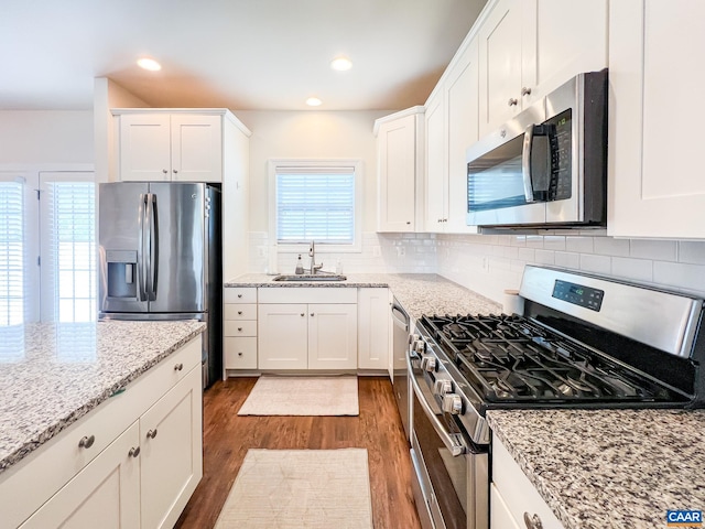 kitchen featuring appliances with stainless steel finishes, a sink, dark wood finished floors, white cabinetry, and recessed lighting