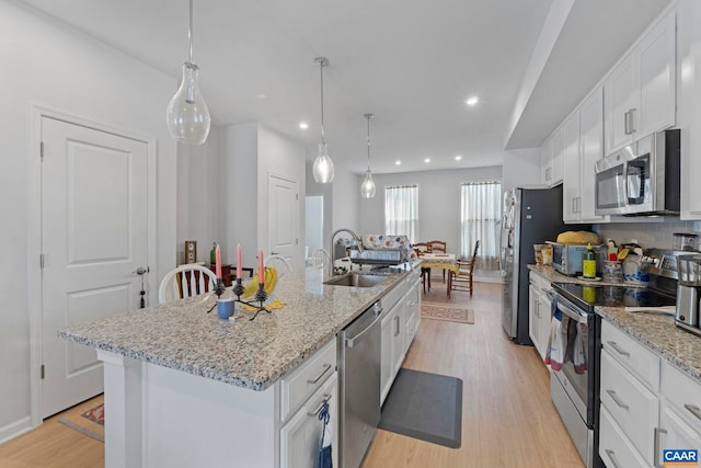 6031 Mccomb St, Crozet, VA 22932 - kitchen featuring stainless steel appliances, an island with sink, light wood finished floors, white cabinets, and light stone counters