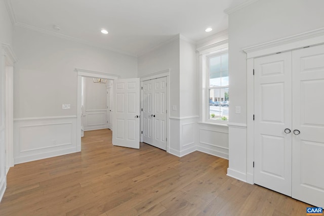 1108 E Jefferson St, Charlottesville, VA 22902 - unfurnished bedroom with multiple closets, ornamental molding, light wood-type flooring, wainscoting, and a decorative wall