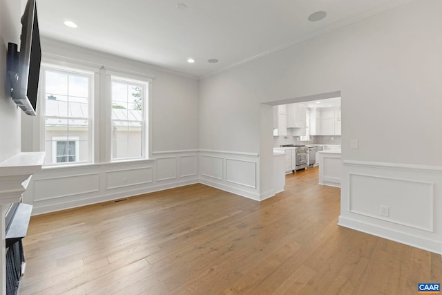 1108 E Jefferson St, Charlottesville, VA 22902 - unfurnished living room featuring a decorative wall, crown molding, light wood-type flooring, and wainscoting