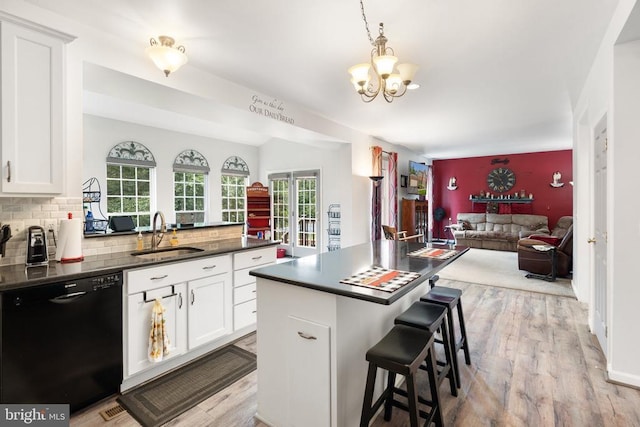  - kitchen with dishwasher, open floor plan, dark countertops, light wood-type flooring, and a breakfast bar