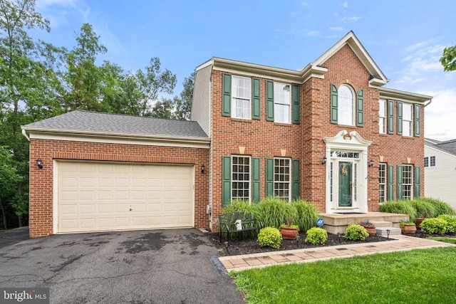  - colonial inspired home featuring brick siding, asphalt driveway, and an attached garage