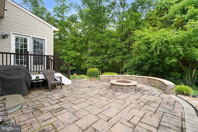  - view of patio with a fire pit, grilling area, and view of wooded area