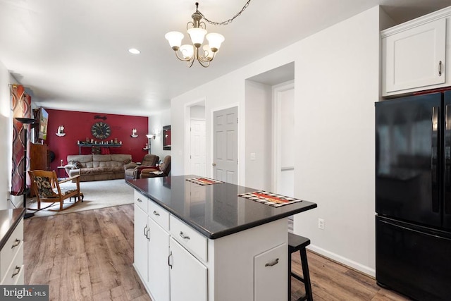  - kitchen with freestanding refrigerator, light wood-style flooring, a center island, dark countertops, and a chandelier