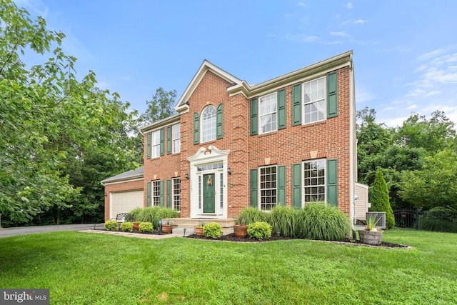  - georgian-style home with a front yard, brick siding, a garage, and asphalt driveway