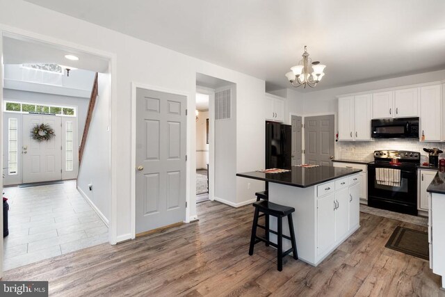  - kitchen featuring black appliances, white cabinetry, dark countertops, a chandelier, and tasteful backsplash