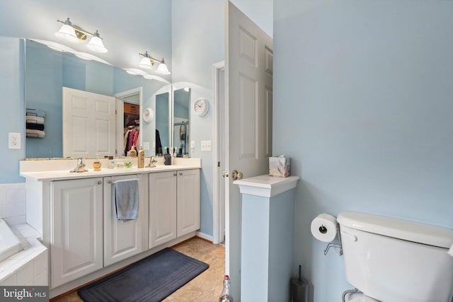 - bathroom featuring double vanity, tiled tub, and a walk in closet