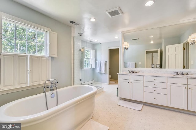  - full bath with recessed lighting, plenty of natural light, toilet, a freestanding bath, and double vanity