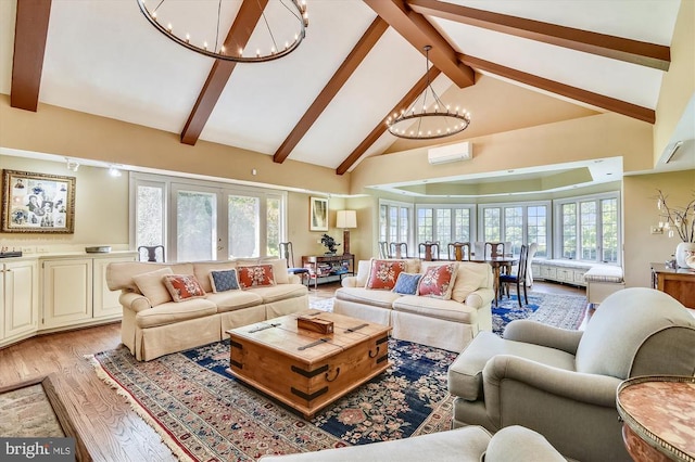 - living area featuring a chandelier, a wall mounted AC, beam ceiling, light wood-type flooring, and healthy amount of natural light