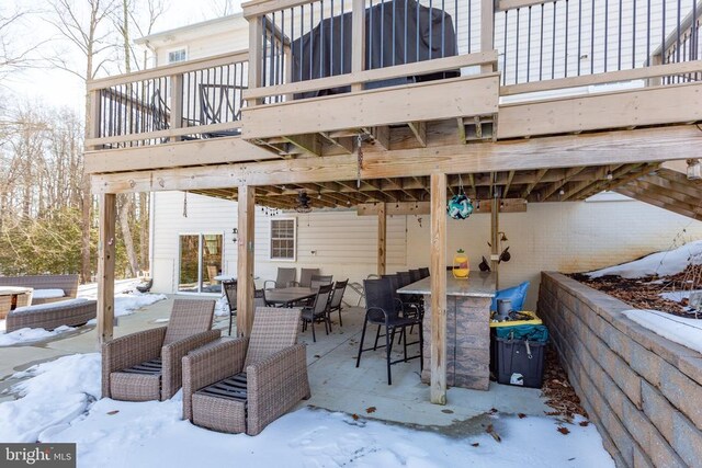 snow covered patio featuring outdoor dining space and a deck