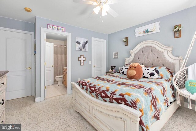 bedroom featuring ensuite bathroom, ceiling fan, dark speckled floor, and baseboards