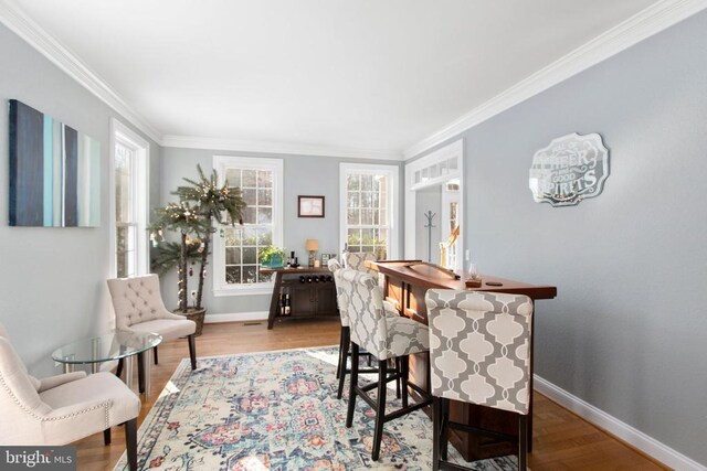 dining room featuring ornamental molding, baseboards, and wood finished floors