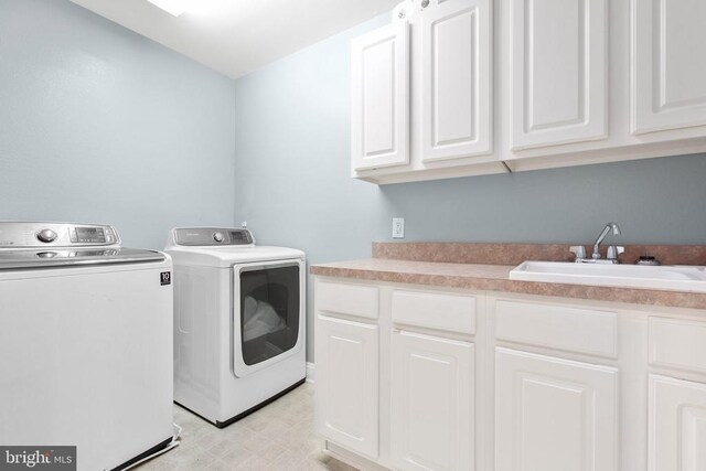 clothes washing area with washer and clothes dryer, cabinet space, and light floors