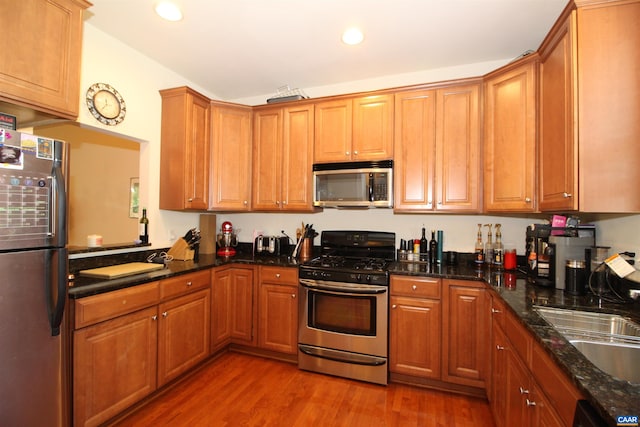 106 Melbourne Prk Cir Unit E, Charlottesville, VA 22901 - kitchen with stainless steel appliances, light wood-style floors, recessed lighting, brown cabinetry, and dark stone countertops